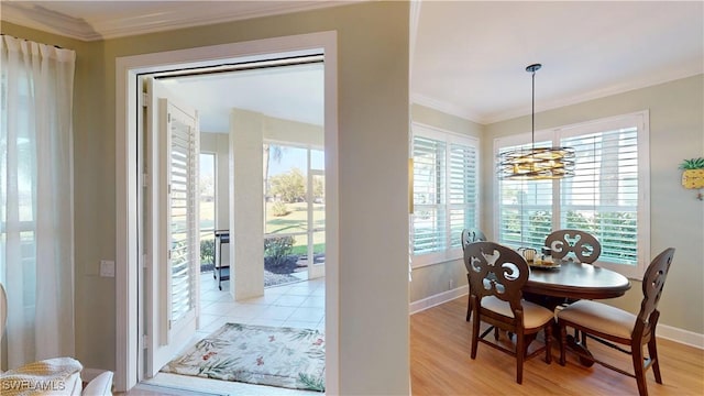 dining space with light wood-type flooring, crown molding, and baseboards