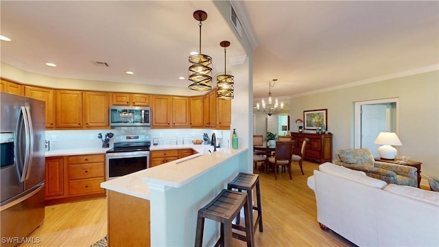 kitchen with a breakfast bar area, a peninsula, a sink, light countertops, and appliances with stainless steel finishes