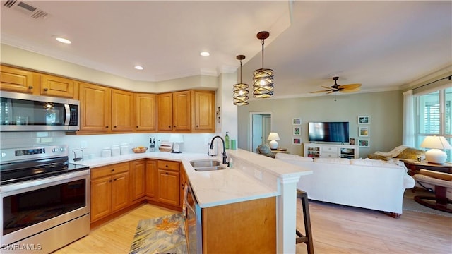 kitchen with stainless steel appliances, a peninsula, a sink, a kitchen breakfast bar, and open floor plan