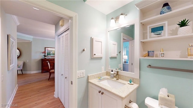 bathroom featuring crown molding, vanity, baseboards, and wood finished floors