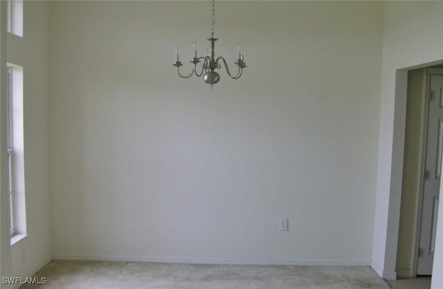 unfurnished dining area with baseboards and a notable chandelier