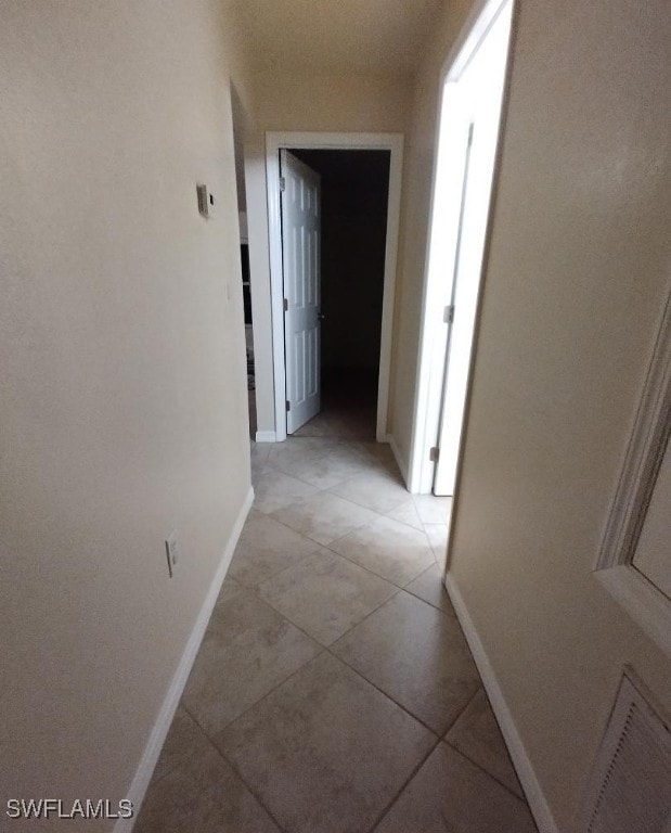 hallway with light tile patterned flooring and baseboards