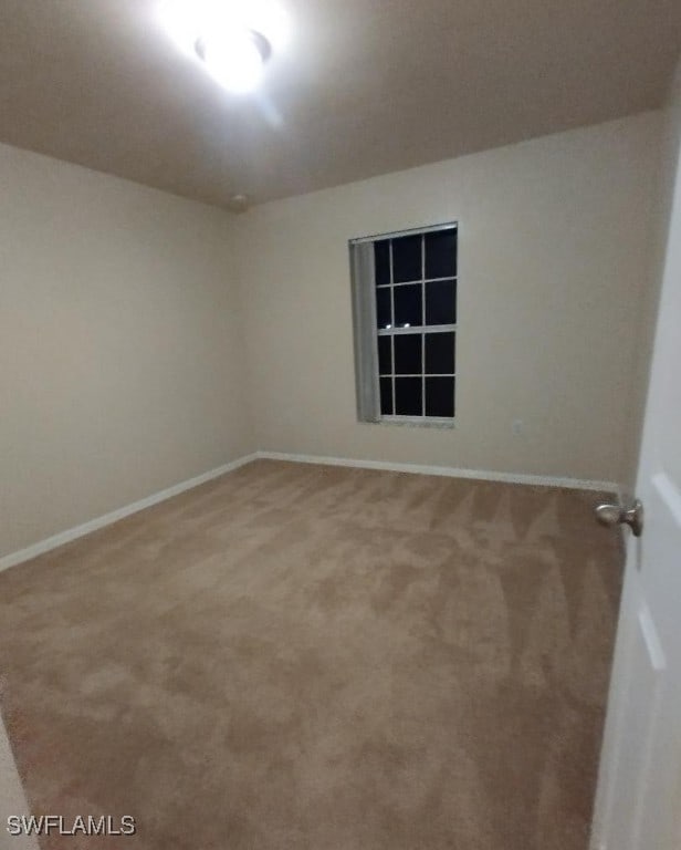 carpeted spare room featuring baseboards