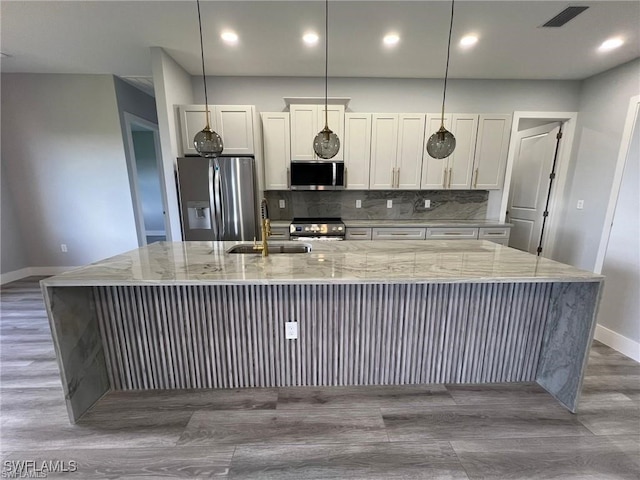 kitchen featuring tasteful backsplash, a large island with sink, stainless steel appliances, baseboards, and visible vents