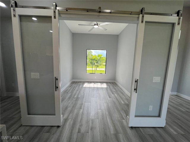 1104 Alaska Ave, Lehigh Acres, FL 33971 - empty room with a barn door, wood finished floors, and ceiling fan