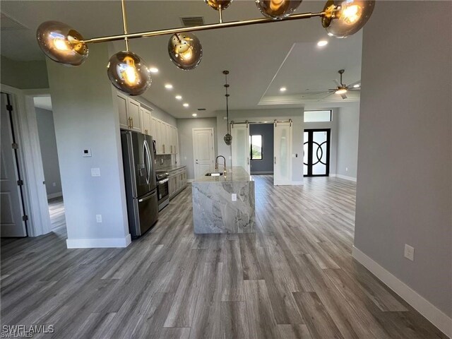 kitchen with stainless steel appliances, visible vents, a barn door, white cabinets, and a sink