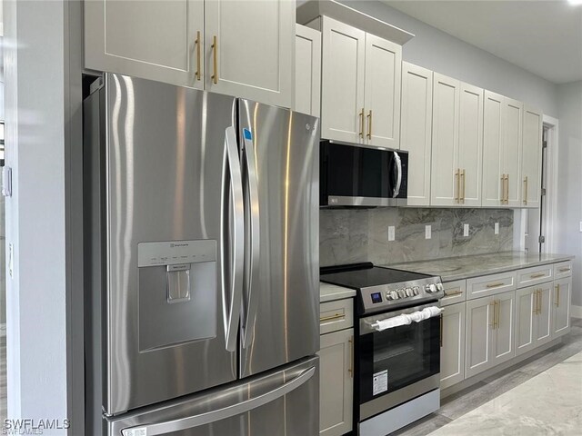 kitchen featuring white cabinets, appliances with stainless steel finishes, light stone counters, and backsplash