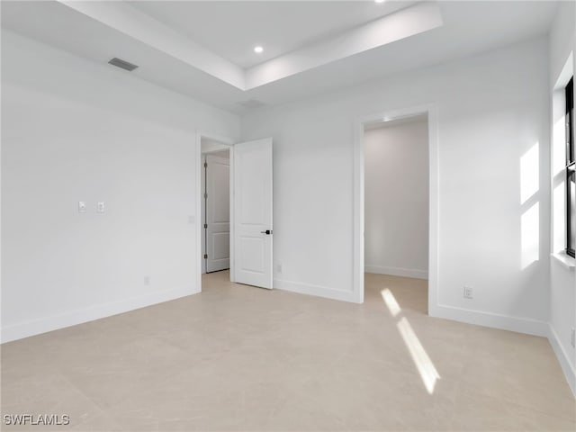 spare room with baseboards, visible vents, and a tray ceiling