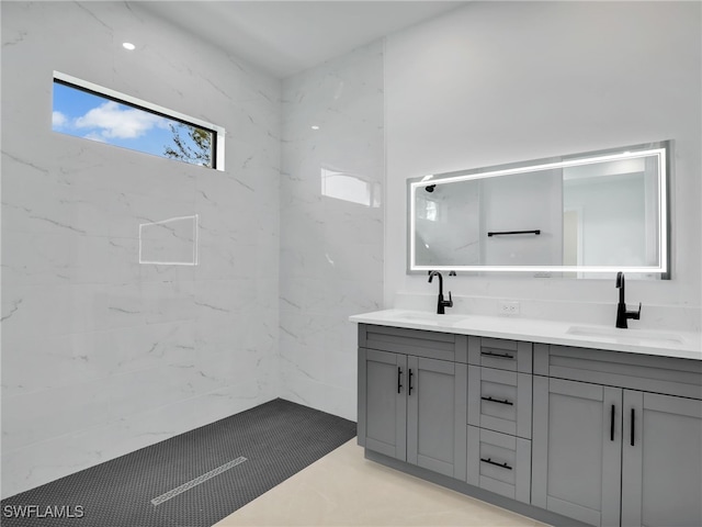 full bath featuring tiled shower, a sink, and double vanity