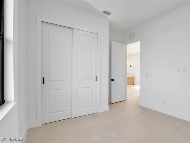 unfurnished bedroom with baseboards, visible vents, and a closet