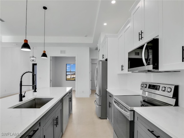 kitchen featuring decorative light fixtures, recessed lighting, gray cabinetry, appliances with stainless steel finishes, and a sink