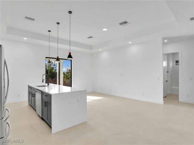 kitchen featuring dishwasher, a raised ceiling, a sink, and visible vents