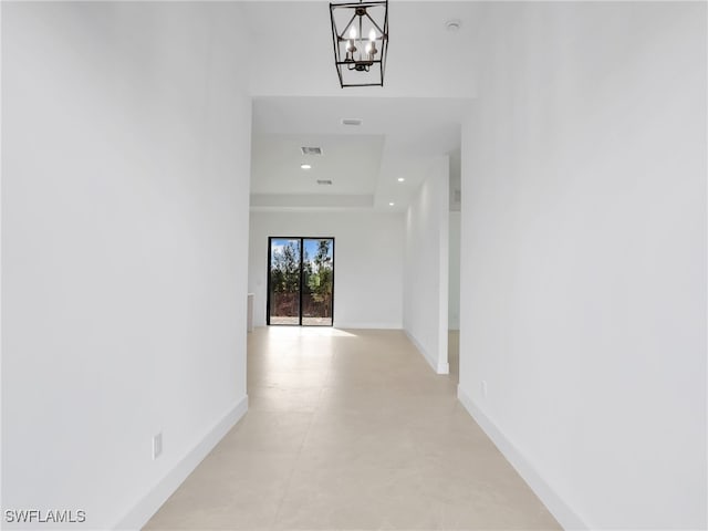 corridor featuring visible vents, baseboards, an inviting chandelier, a tray ceiling, and recessed lighting