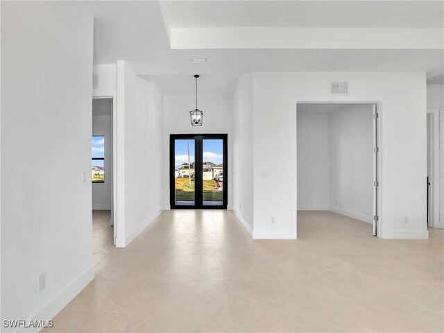 empty room featuring baseboards, visible vents, and french doors