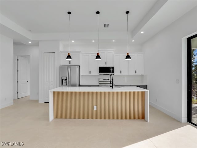 kitchen featuring a sink, visible vents, appliances with stainless steel finishes, tasteful backsplash, and a center island with sink