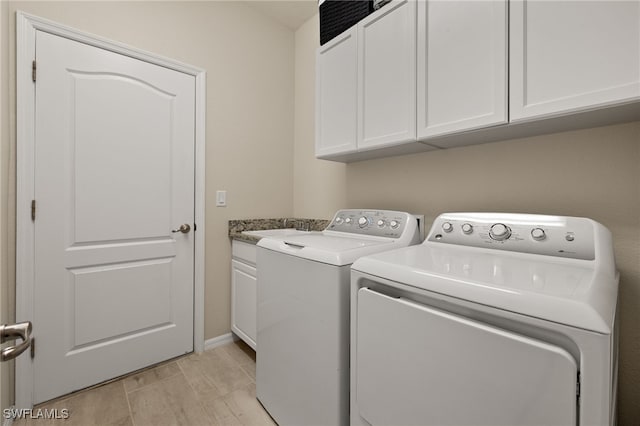 clothes washing area with wood finish floors, washer and clothes dryer, cabinet space, and baseboards