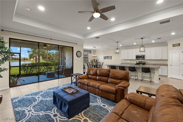 living room with light tile patterned floors, recessed lighting, visible vents, a raised ceiling, and crown molding