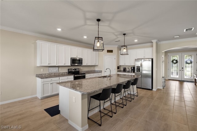 kitchen with stainless steel appliances, a sink, visible vents, a kitchen breakfast bar, and french doors