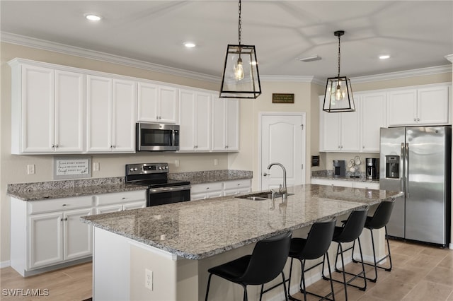 kitchen with appliances with stainless steel finishes, white cabinets, a sink, and ornamental molding