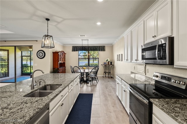 kitchen featuring stainless steel appliances, white cabinets, a sink, and ornamental molding