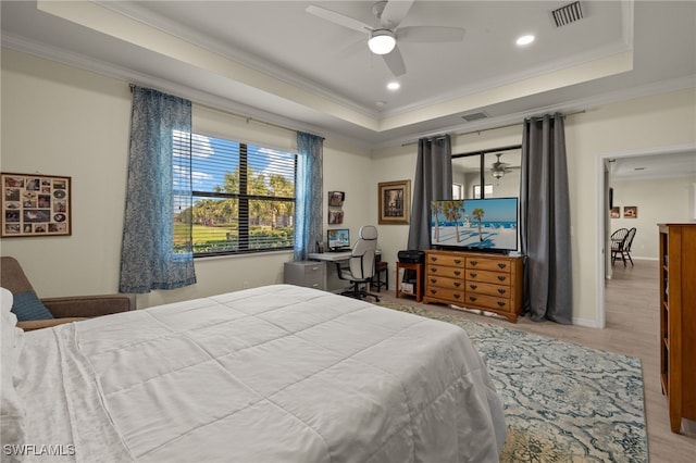 bedroom with visible vents, ornamental molding, a raised ceiling, and wood finished floors