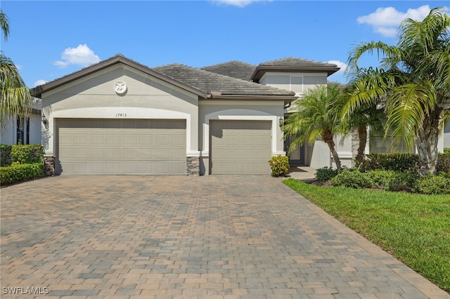 view of front of house with an attached garage, stone siding, decorative driveway, and stucco siding