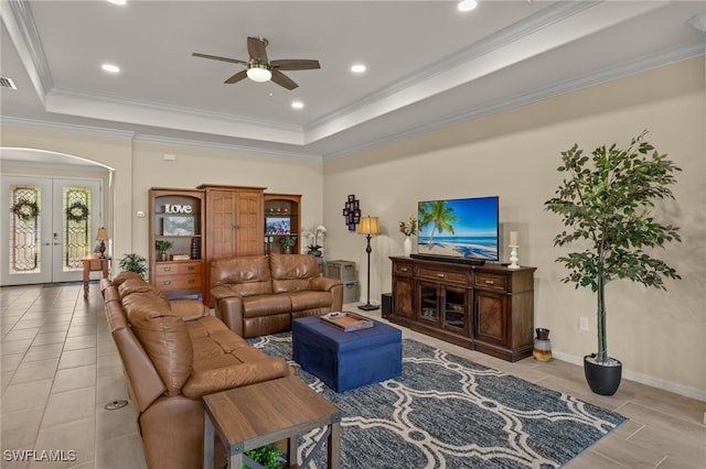 living room with ornamental molding, arched walkways, a raised ceiling, and french doors