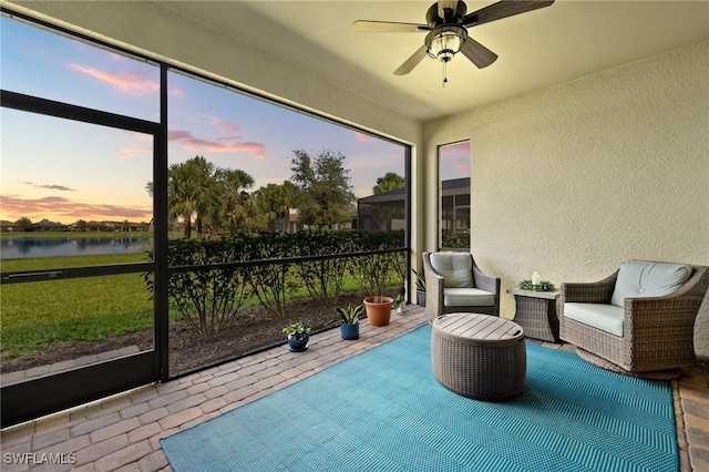 sunroom / solarium with a ceiling fan and a water view