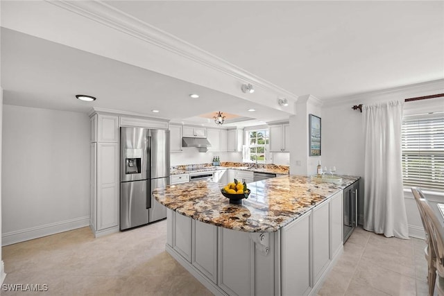 kitchen featuring light stone counters, a peninsula, stainless steel appliances, crown molding, and under cabinet range hood