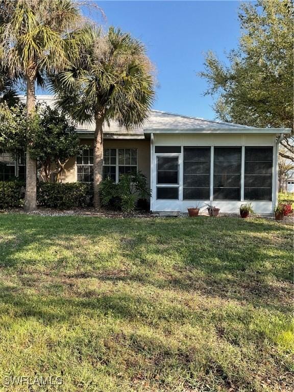 back of house featuring a lawn and a sunroom