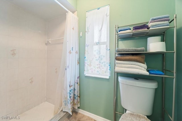 full bathroom with a stall shower, toilet, and baseboards