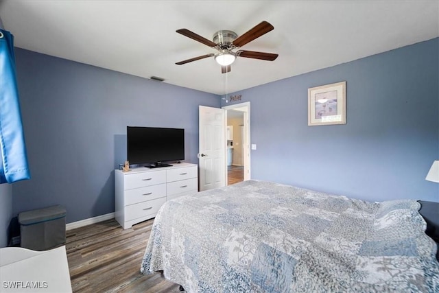 bedroom with a ceiling fan, wood finished floors, visible vents, and baseboards