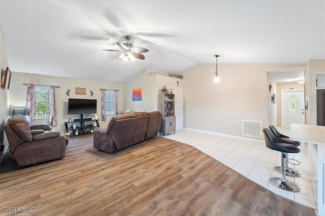 living area featuring ceiling fan, visible vents, vaulted ceiling, and wood finished floors