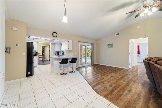 kitchen featuring lofted ceiling, a peninsula, open floor plan, light countertops, and freestanding refrigerator