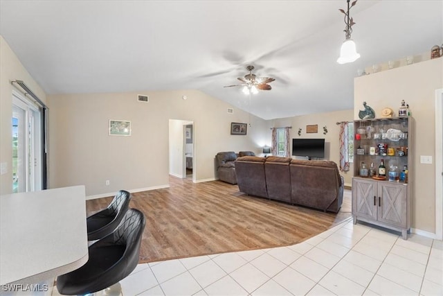 living room with plenty of natural light, visible vents, vaulted ceiling, and light tile patterned floors