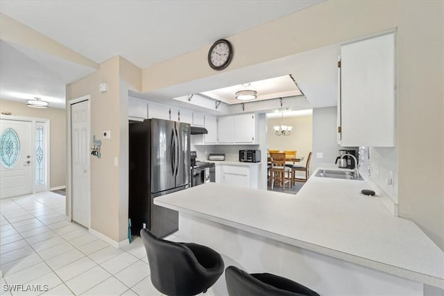 kitchen featuring a tray ceiling, light countertops, appliances with stainless steel finishes, a sink, and a peninsula