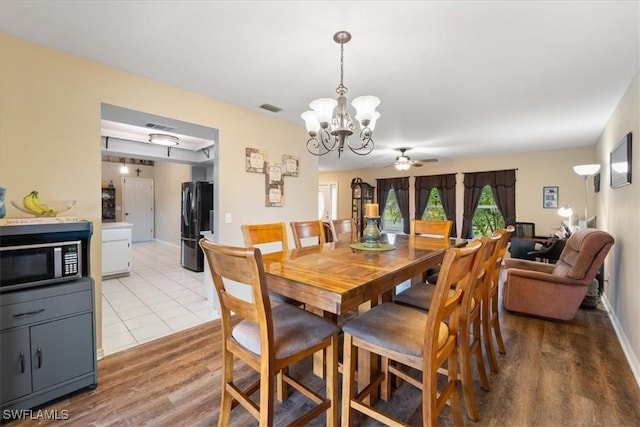 dining area with light wood-style floors, baseboards, visible vents, and ceiling fan with notable chandelier