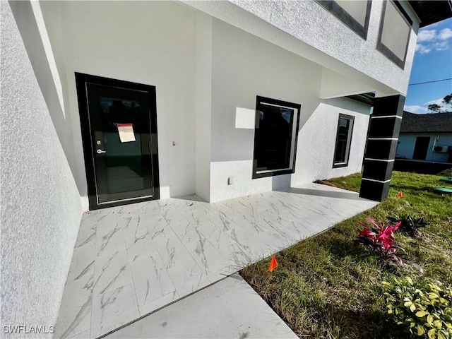 entrance to property featuring a patio area and stucco siding