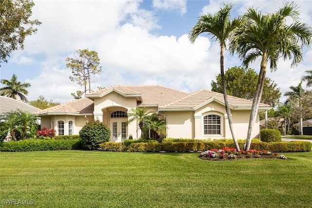 view of front of property with stucco siding, a front yard, and a tile roof