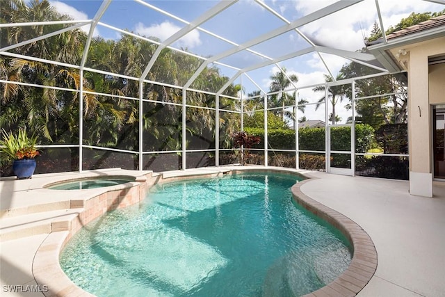 view of pool featuring glass enclosure, a pool with connected hot tub, and a patio area