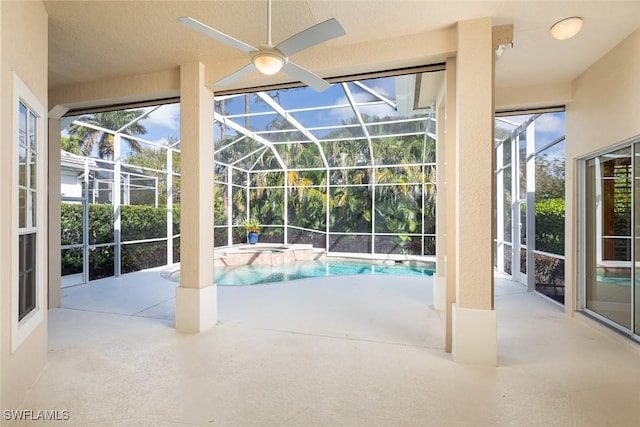 view of pool with a patio area, glass enclosure, a pool with connected hot tub, and a ceiling fan