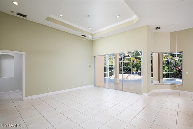 spare room with a tray ceiling, a high ceiling, light tile patterned floors, and visible vents