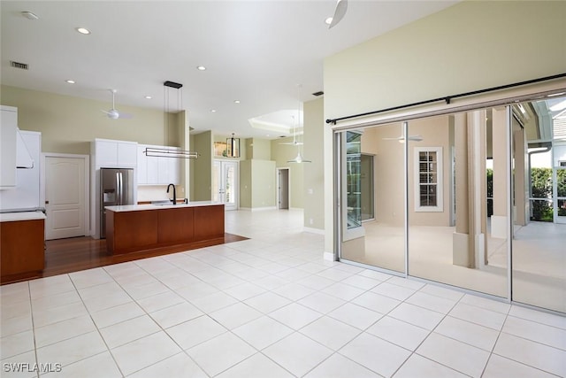 kitchen featuring visible vents, open floor plan, light countertops, stainless steel refrigerator with ice dispenser, and a sink