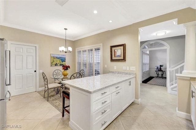 11596 Quail Village Way, Naples, FL 34119 - kitchen featuring a breakfast bar area, white cabinets, a peninsula, light tile patterned flooring, and ornate columns