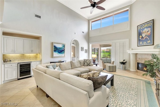 11596 Quail Village Way, Naples, FL 34119 - living room with beverage cooler, high vaulted ceiling, ornamental molding, ceiling fan, and a premium fireplace