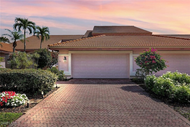 11596 Quail Village Way, Naples, FL 34119 - view of front facade featuring a tile roof, decorative driveway, stucco siding, and an attached garage