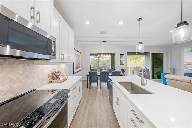 kitchen featuring a sink, white cabinetry, visible vents, decorative backsplash, and stainless steel microwave