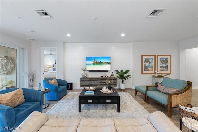 living area with recessed lighting, visible vents, baseboards, and wood finished floors