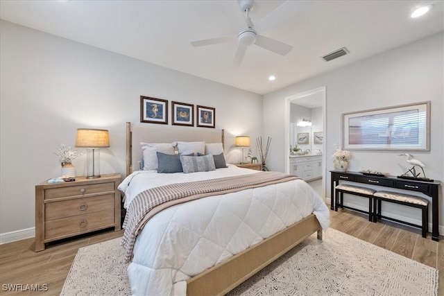 bedroom with recessed lighting, wood finished floors, visible vents, baseboards, and ensuite bath