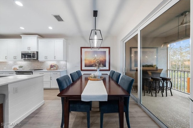 dining area with light wood-type flooring, visible vents, and recessed lighting